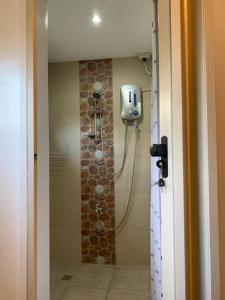 a shower in a bathroom with a stone wall at MAGAYON BLUE HOUSE IN THE HEART OF LEGAZPI in Legazpi