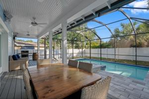 a patio with a wooden table and chairs and a swimming pool at Luxury Retreat Hot Tub for 8 in Stylish Bungalow in Tampa