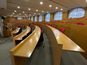 an empty lecture hall with desks and red chairs at Casa Diocesana VIA LUCIS in Santiago de Compostela