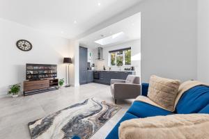 a living room with a blue couch and a kitchen at SERCASA - Woodside Park - North Finchley in Whetstone