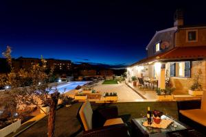 a house with a patio and a pool at night at Romantic stone villa with pool, panoramic sea view near the beach - by Traveler tourist agency Krk ID 2134 in Vrbnik