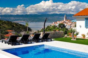 a villa with a swimming pool and a view of a city at Romantic stone villa with pool, panoramic sea view near the beach - by Traveler tourist agency Krk ID 2134 in Vrbnik