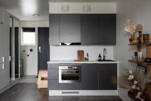 a kitchen with gray cabinets and an oven at Viihtyisä yksiö, oma parkkipaikka, wifi, Aino Areena 300m in Järvenpää