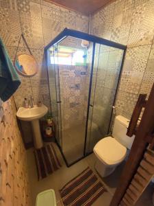 a bathroom with a shower and a toilet and a sink at Casa Raízes Capão in Vale do Capao