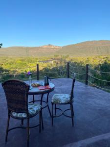 a table and two chairs on a patio with a view at Casa Raízes Capão in Vale do Capao