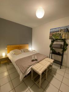 een slaapkamer met een bed met een bank en een schilderij bij Au pied de la cité, T3 au calme in Carcassonne