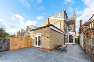 a brick house with a patio and a fence at SERCASA - Woodside Park - North Finchley in Whetstone