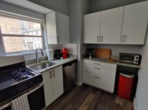 a small kitchen with white cabinets and a sink at Cozy 1BDR In Center City Philly Hosted By StayRafa in Philadelphia