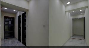 einen Flur eines Gebäudes mit weißen Wänden und Türen in der Unterkunft HOTEL GREENITY in Ahmedabad