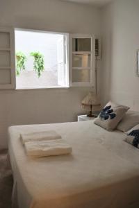 1 dormitorio con 1 cama blanca y ventana en Peixe Crew Centro en Búzios