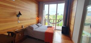 Pousada Bracatinga في بوم ريتيرو: غرفة نوم بسرير ونافذة كبيرة
