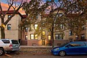 two cars parked in a parking lot in front of a building at Cozy and Inviting Two-Bedroom Apartment - Sunnyside 3F in Chicago