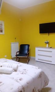 Habitación amarilla con 2 camas y silla en Villa helios en Barletta