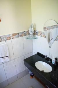La salle de bains est pourvue d'un lavabo et d'un miroir. dans l'établissement Casa a 5 min do Balneario Coroados - Guaratuba PR, à Guaratuba