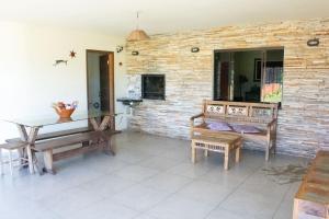 un salon avec une table, des bancs et un mur en briques dans l'établissement Casa a 5 min do Balneario Coroados - Guaratuba PR, à Guaratuba