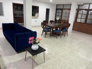 COOL HOUSE 24Horas في أراوكا: غرفة معيشة مع أريكة زرقاء وطاولة وكراسي