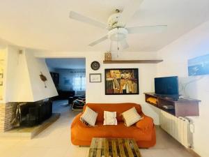 um sofá laranja na sala de estar com uma ventoinha de tecto em Casa Gran em Calonge