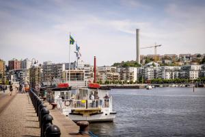 Ein Boot liegt neben einem Fluss mit Gebäuden vor Anker. in der Unterkunft Cozy gem in Stockholm