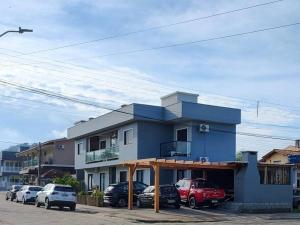 a blue building with cars parked in front of it at Apartamento na praia Garopaba San Pietro Sc loft 102 in Garopaba