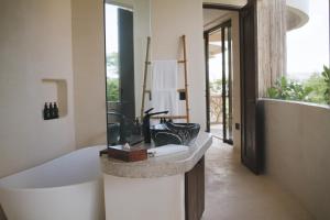 a bathroom with a bath tub and a sink at Kan Tulum in Tulum