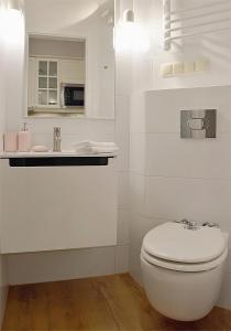 een witte badkamer met een toilet en een wastafel bij Art Apartments w centrum Krakowa (Śródmieście, Stradom) in Krakau