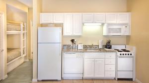 a kitchen with white cabinets and a white refrigerator at Club Wyndham Beach Street Cottages in Destin