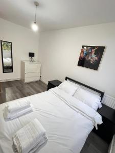 - une chambre dotée d'un lit blanc avec des draps et des oreillers blancs dans l'établissement Entire 3 Bedroom Luxury Apartment in London with Private Balcony, à Londres