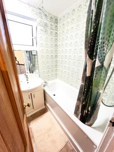 ein Badezimmer mit einer Badewanne und einem Waschbecken in der Unterkunft Entire 3 Bedroom Luxury Apartment in London with Private Balcony in London