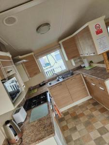 a small kitchen with wooden cabinets and a window at H9 Fairway Holiday Park Sandown in Sandown