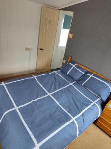 a bed with a blue comforter in a bedroom at H9 Fairway Holiday Park Sandown in Sandown