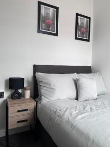 a white bedroom with a bed and a night stand at Cosy Home in Manchester in Manchester