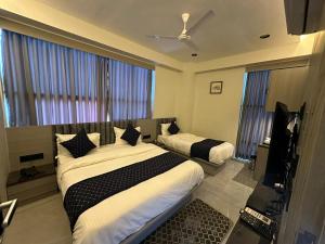 a bedroom with two beds and a flat screen tv at HOTEL ASIANA SKY Motera Ahmedabad in Ahmedabad