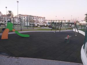 Un patio de recreo vacío con columpios y un parque infantil. en Apartamento Taymar Daniel, en Chiclana de la Frontera