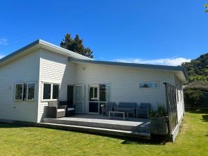 a white house with a deck with furniture on it at Graydon Grove in Kaiteriteri