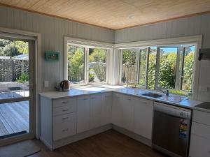 a kitchen with white cabinets and a large window at Graydon Grove in Kaiteriteri