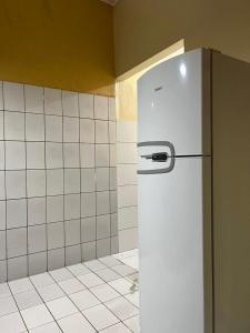 um frigorífico branco numa cozinha com uma parede em azulejo em Casa inteira na Praia do Frances em Marechal Deodoro