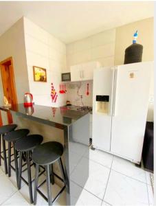 La cuisine est équipée d'un comptoir avec tabourets et d'un réfrigérateur. dans l'établissement Residencial Caravelle, à Passo de Torres