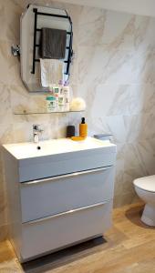 La salle de bains est pourvue d'un lavabo blanc et d'un miroir. dans l'établissement Villa Maëlla, studio rez-de-jardin, à Saint-Michel-la-Forêt