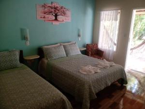 a bedroom with two beds and a window at Pousada Recanto do Sossego in São Thomé das Letras