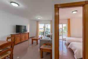 a bedroom with a bed and a tv and a couch at Apartamentos Solset Nerja in Nerja