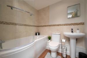 a bathroom with a toilet and a sink and a bath tub at Stunning 3 bed with parking & garden in Market Rasen