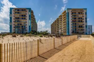two tall buildings on the beach next to a fence at Braemar Towers in Ocean City