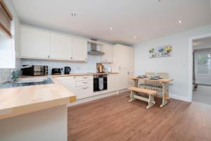a kitchen with white cabinets and a wooden table at Stunning 3 bed with parking & garden in Market Rasen