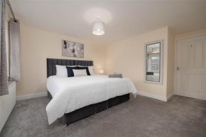 um quarto com uma cama grande e lençóis brancos em Stunning 3 bed with parking & garden em Market Rasen