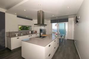 a kitchen with white cabinets and a counter top at Villa Harmonia by Place OverSea With Indoor Pool in Ponta do Sol