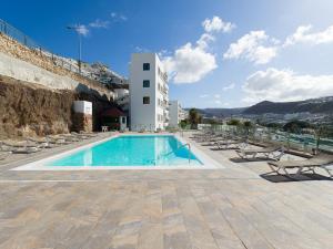 a swimming pool with chairs and a building at Haiti 306 vista al mar in Mogán