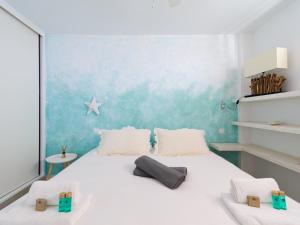 a bedroom with a white bed with a blue wall at Haiti 306 vista al mar in Mogán +25 photos
