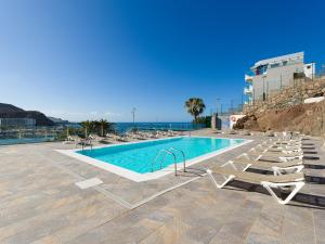 a swimming pool with lounge chairs and the ocean at Haiti 306 vista al mar in Mogán