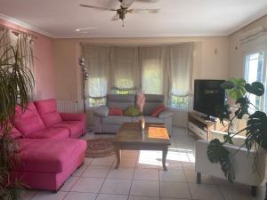 ein Wohnzimmer mit rosa Sofas und einem TV in der Unterkunft Villa Benjamina avec piscine climatisée in Altea