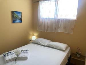 a bedroom with a bed with white pillows and a window at Murph's Surf Shacks in Rivas
